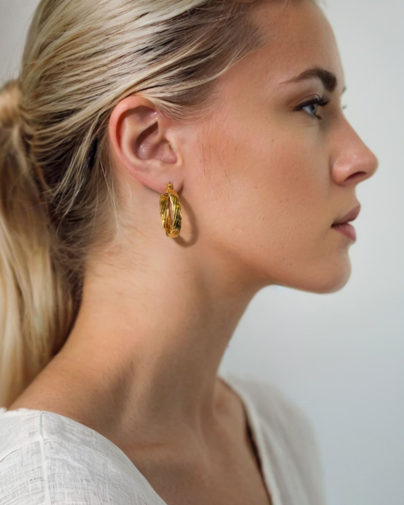 Drift Gold Hoop Earrings by Lavana on model wide polished hoops with deep groove texture