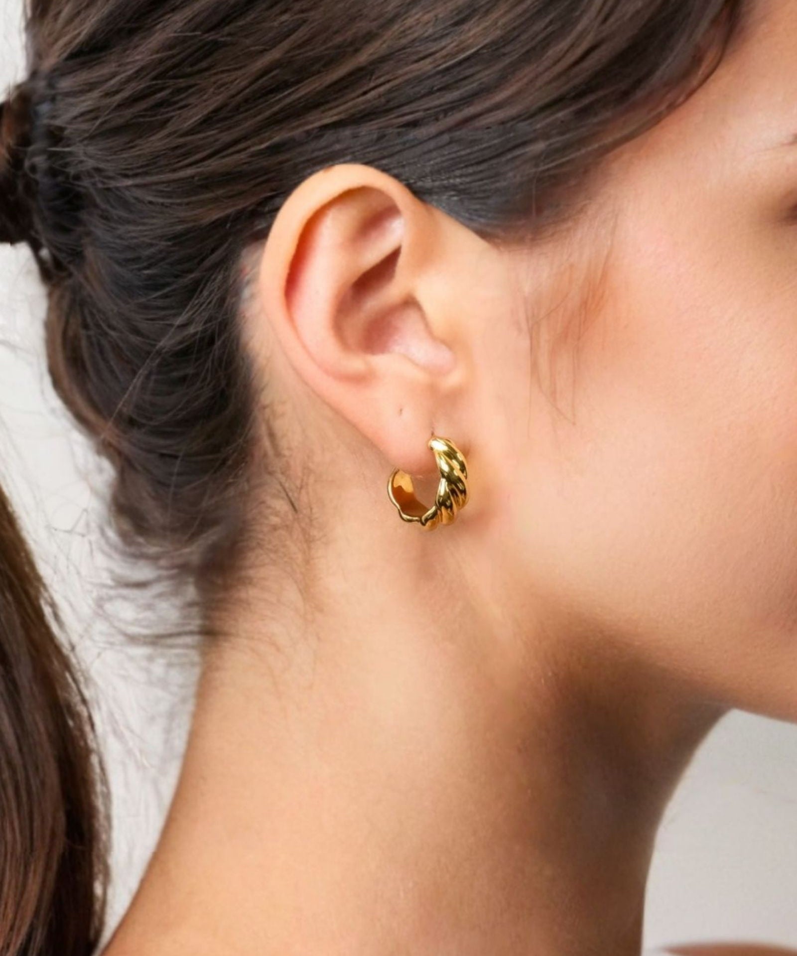 Eve Twist Gold Hoop Earrings by LAVANA on model compact huggie hoop with intertwined twist