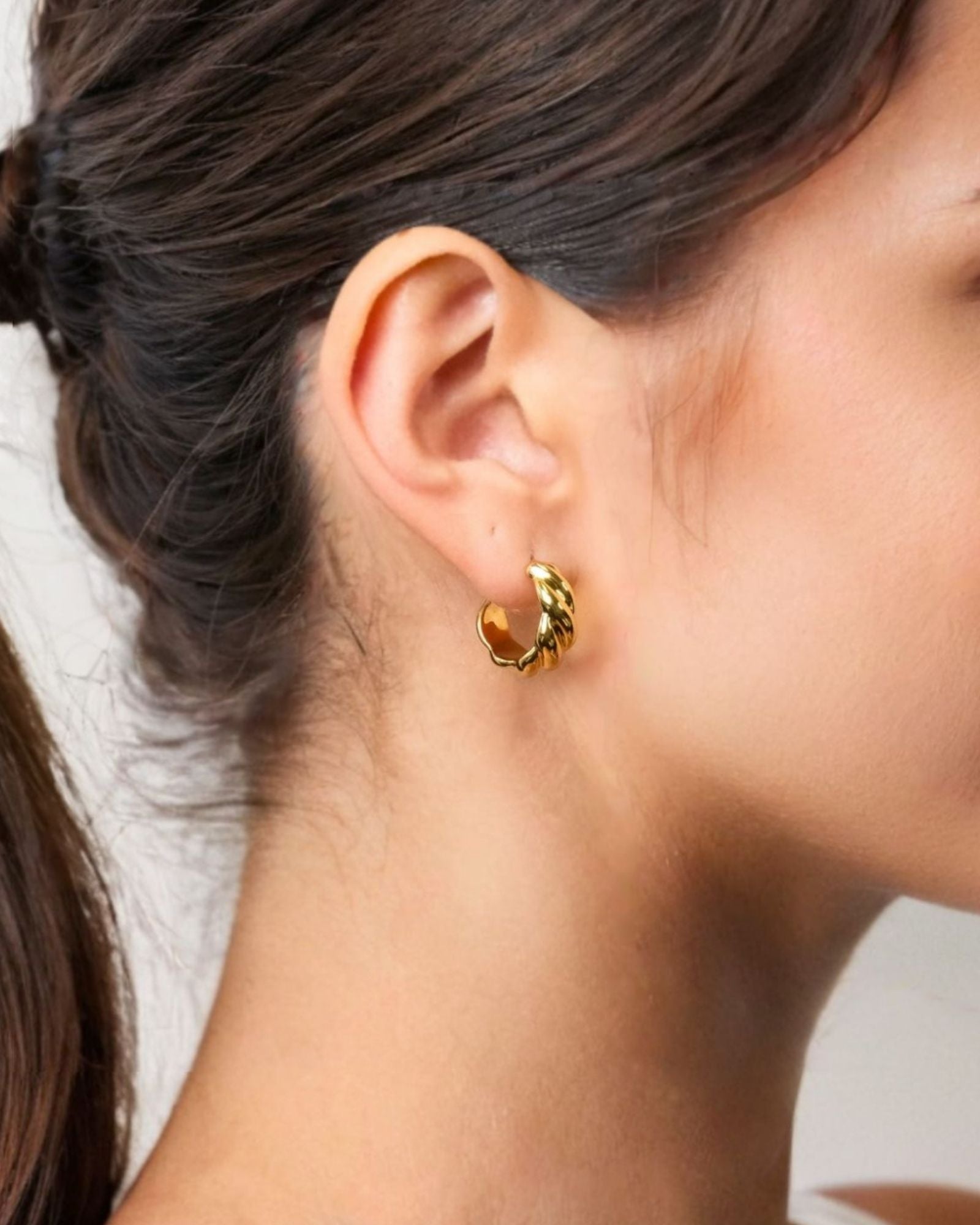 Eve Twist Gold Hoop Earrings by LAVANA on model compact huggie hoop with intertwined twist
