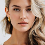 Floating Pebble Gold Huggie Earrings by Lavana, on model; polished pebble domes on bold huggie