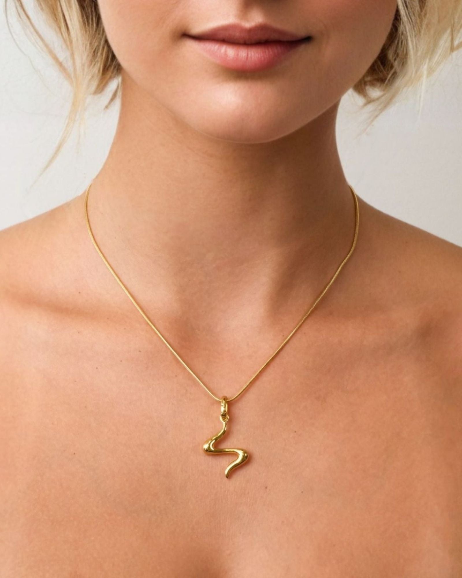 Fluid Gold Pendant by LAVANA on model with sculptural wave silhouette