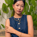 Fluid gold pendant by Lavana, on model; with sculptural wave silhouette