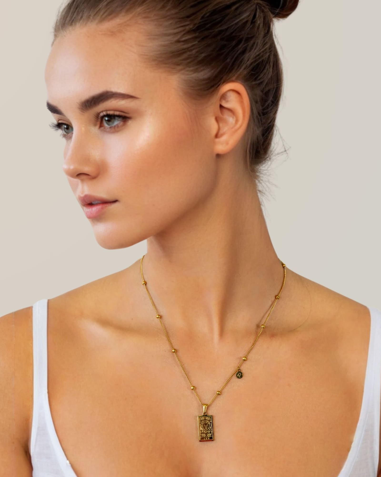 Leo Gold Zodiac Tag Necklace by Lavana, on model; engraved tag with constellation on beaded chain, front 