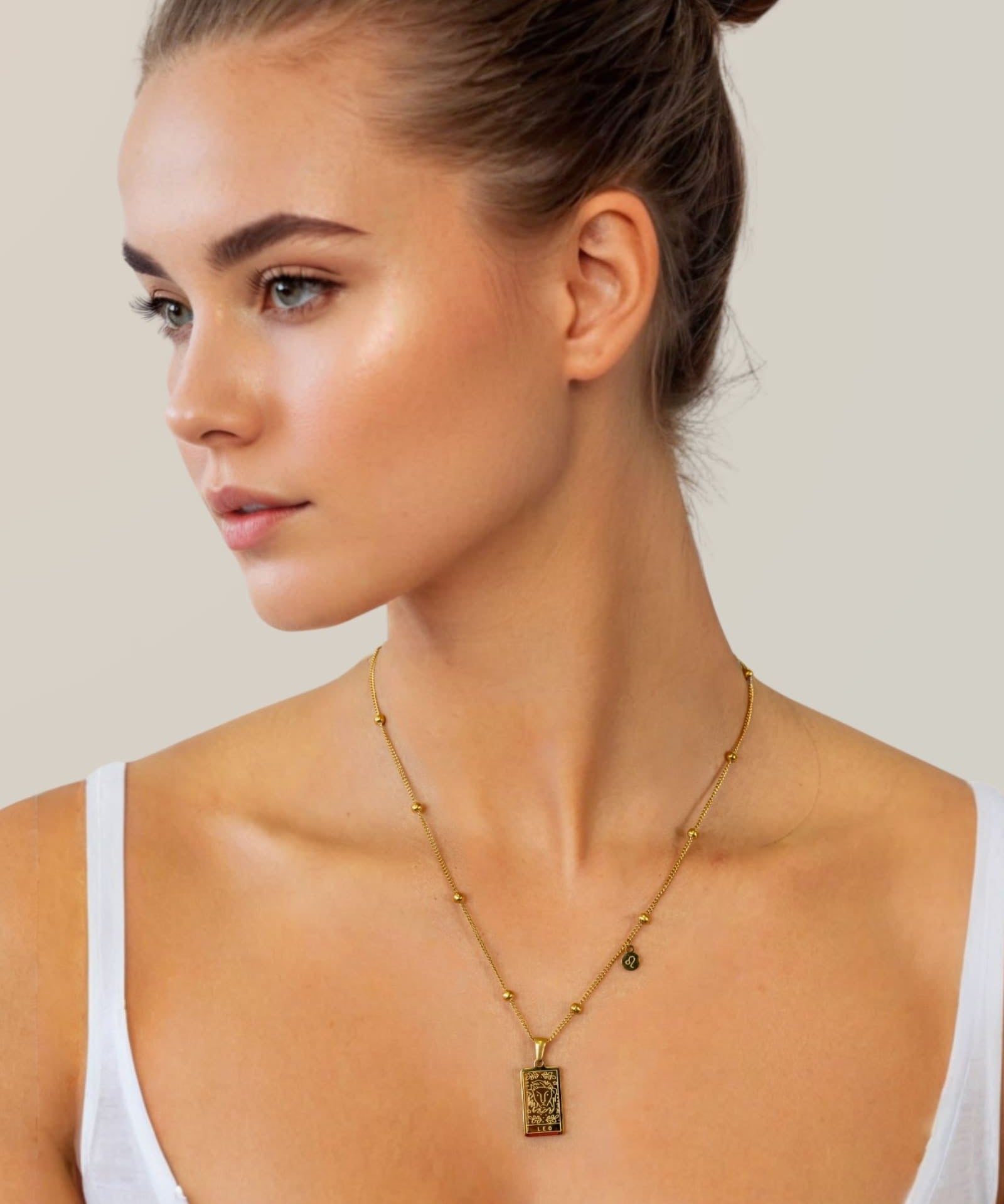 Leo Gold Zodiac Tag Necklace by Lavana, on model; engraved tag with constellation on beaded chain, front 
