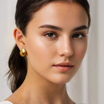 Liquid Arc Gold Earrings by Lavana, on model; sculptural tapered arc with high gloss finish