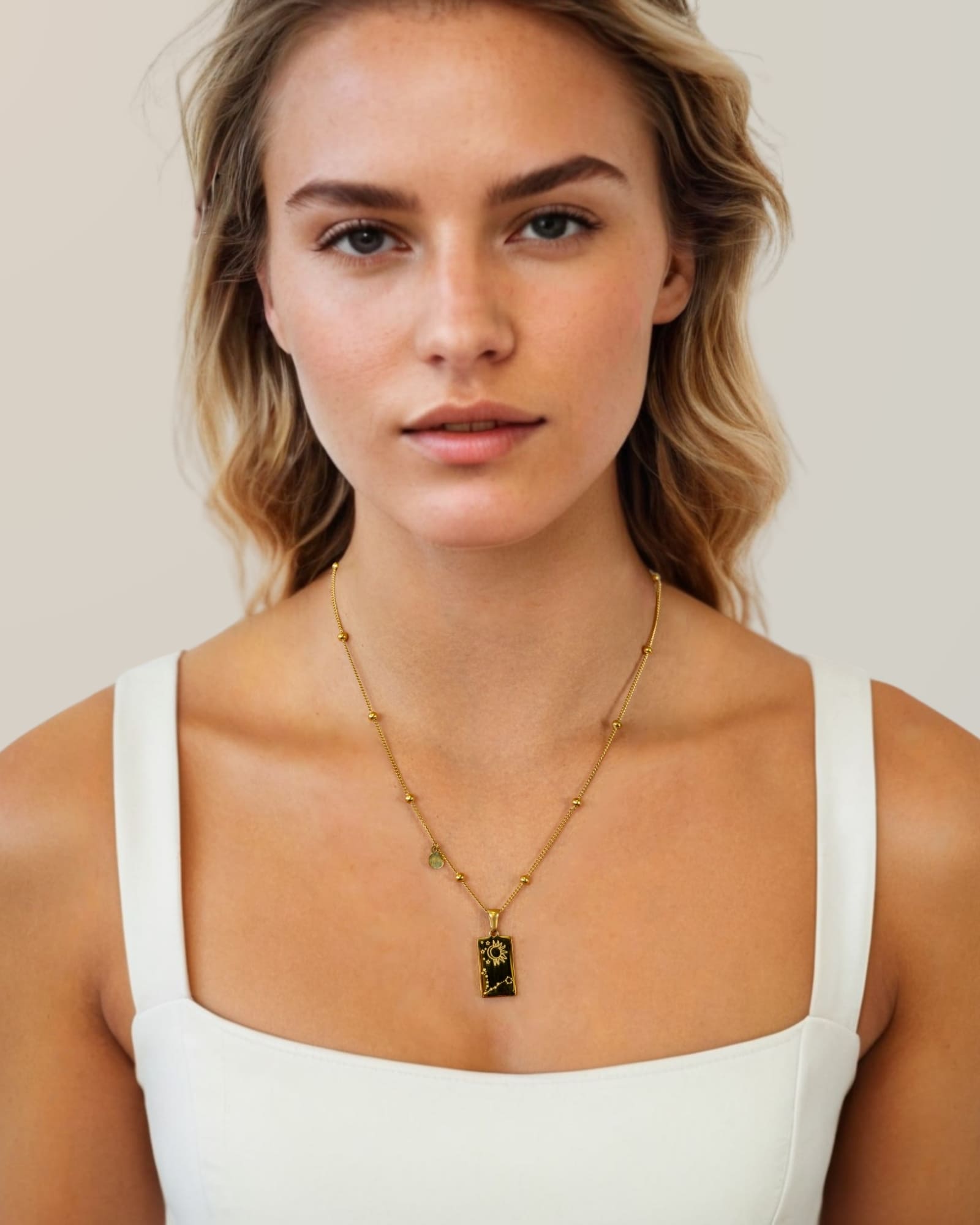 Pisces Gold Zodiac Tag Necklace by Lavana, on model; engraved tag on beaded chain, back