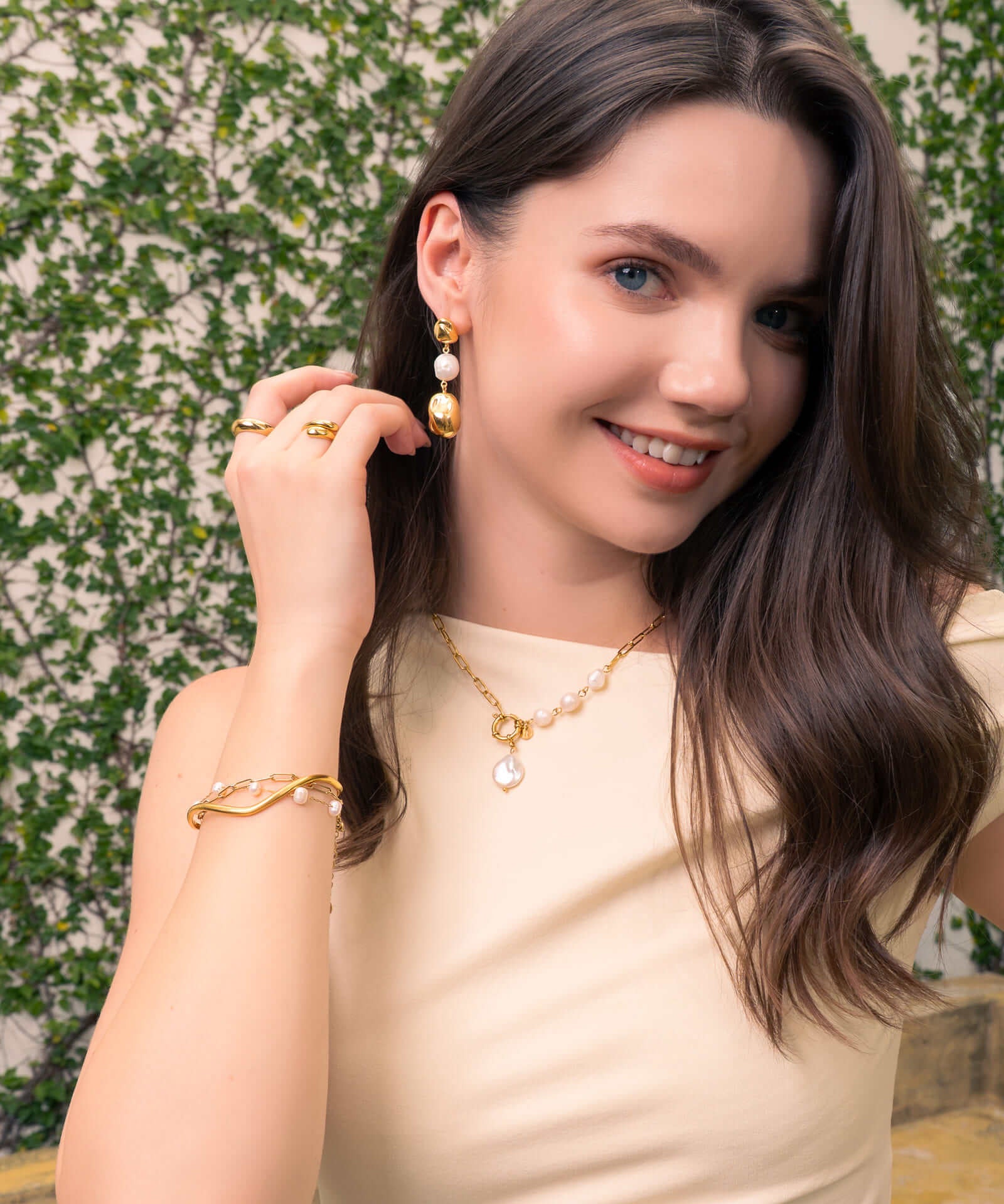 Positano gold pearl necklace by Lavana, on model; asymmetric paperclip links with baroque pearl drop 