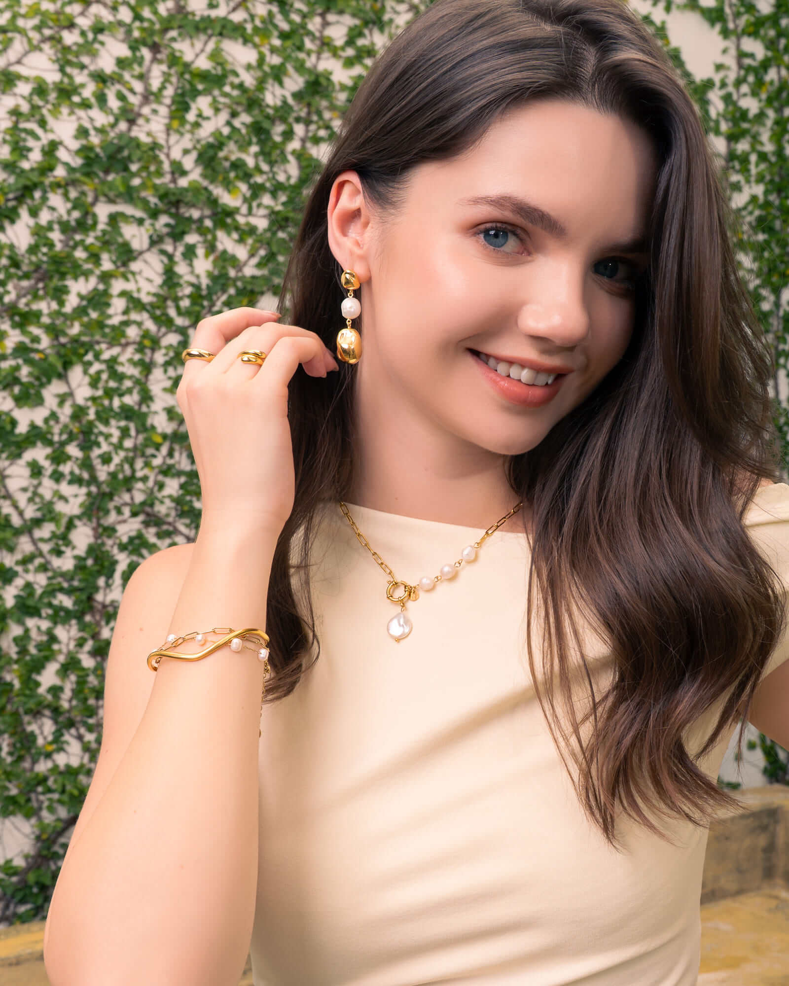 Positano gold pearl necklace by Lavana, on model; asymmetric paperclip links with baroque pearl drop 