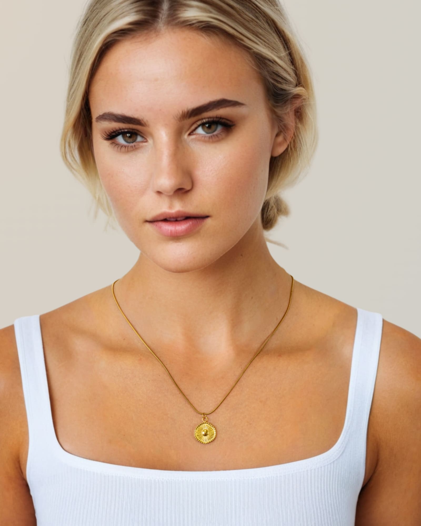 Ray of Sun gold pendant necklace by Lavana, on model; engraved sunburst coin