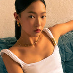 Rhythm Gold M Hoop Earrings by LAVANA, on model; wide polished dress hoops with light textured grooves