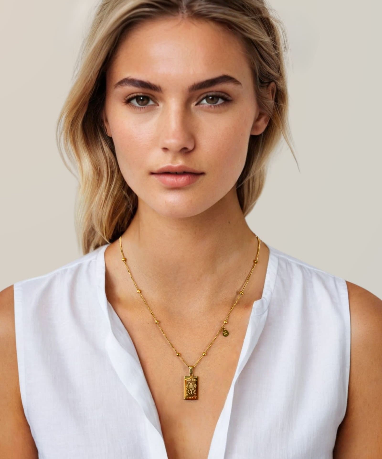 Scorpio Gold Zodiac Tag Necklace by Lavana, on model; engraved tag front and back on beaded station chain, front