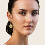 Starburst Charm Gold Huggie Earrings by Lavana, on model; textured  disc with raised star motif