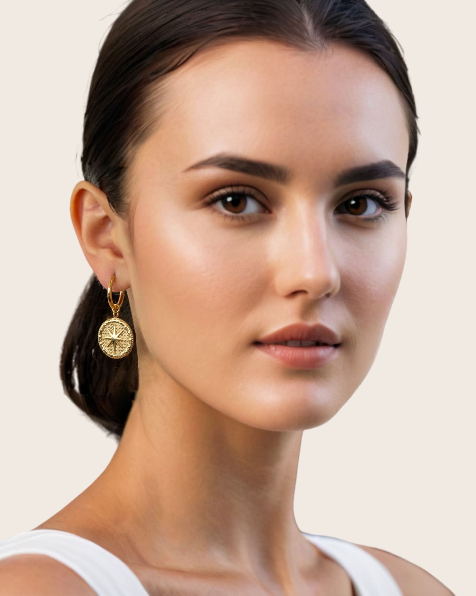 Starburst Charm Gold Huggie Earrings by Lavana, on model; textured  disc with raised star motif