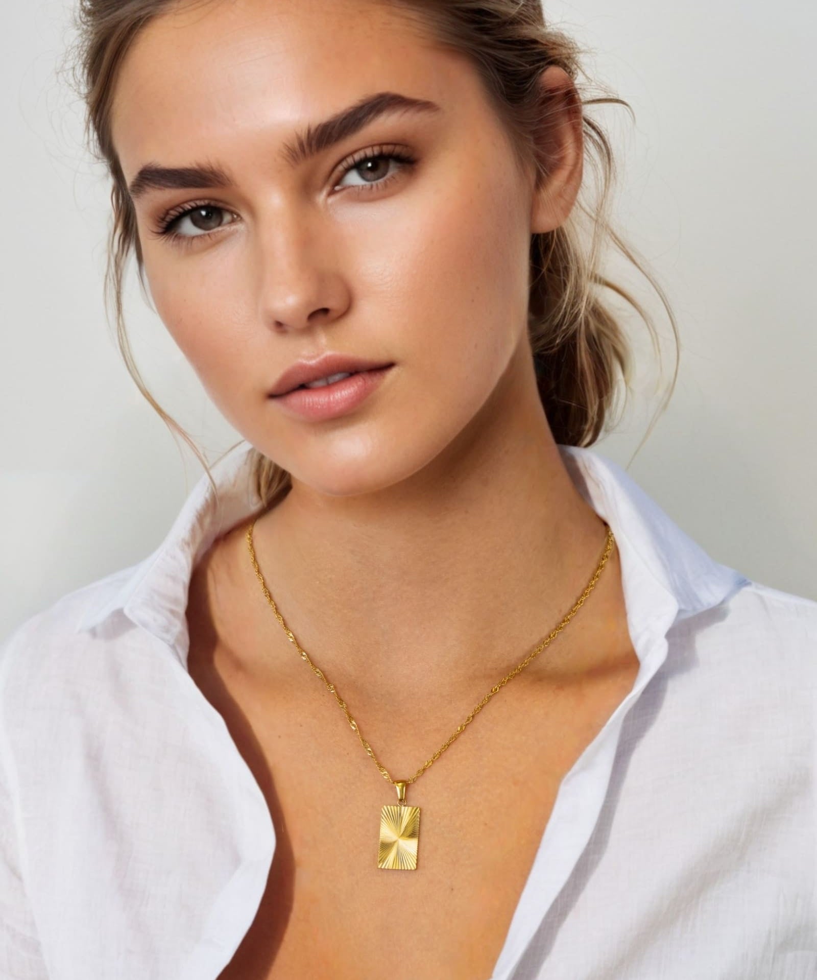 Sunburst Gold Tag Necklace by Lavana, on model; sunburst engraved rectangle tag on fine chain 