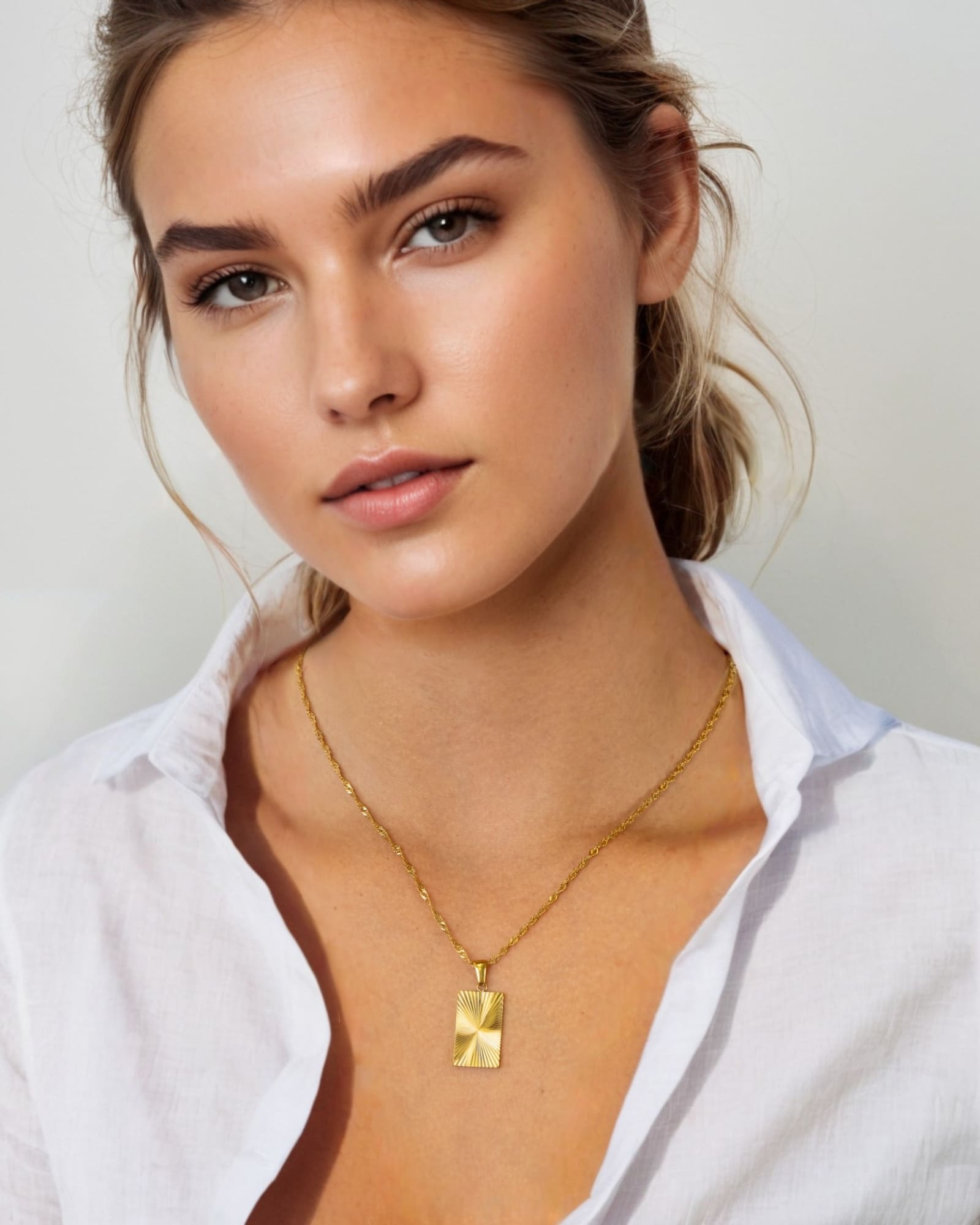 Sunburst Gold Tag Necklace by Lavana, on model; sunburst engraved rectangle tag on fine chain 