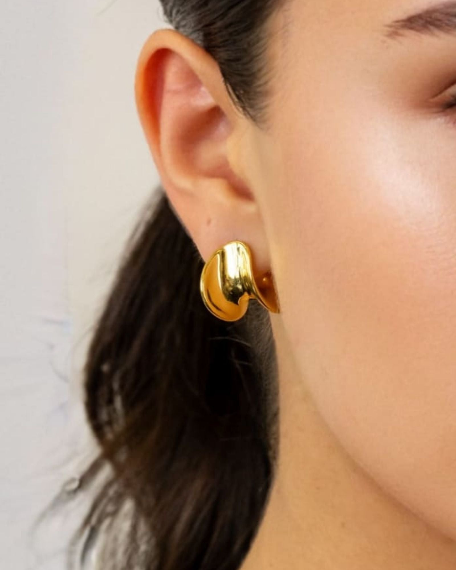 Swell Gold Stud Earrings by LAVANA on model with polished wave curve studs