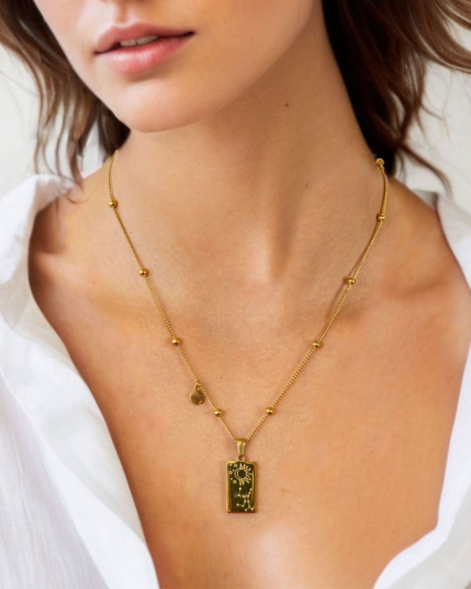 Virgo Gold Zodiac Tag Necklace by Lavana, on model; engraved tag front and back on beaded chain, back 