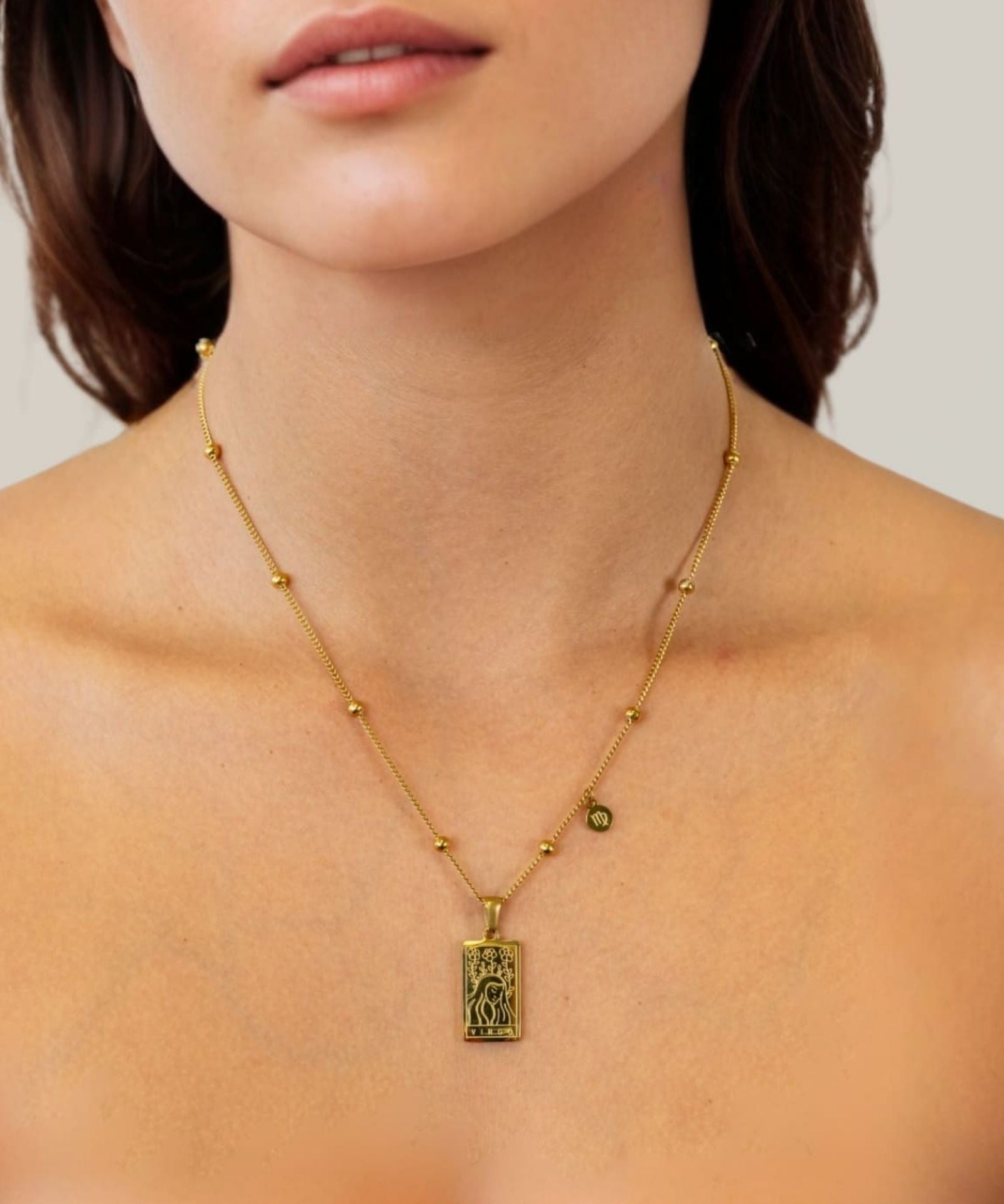 Virgo Gold Zodiac Tag Necklace by Lavana, on model; engraved tag with constellation on beaded chain, front