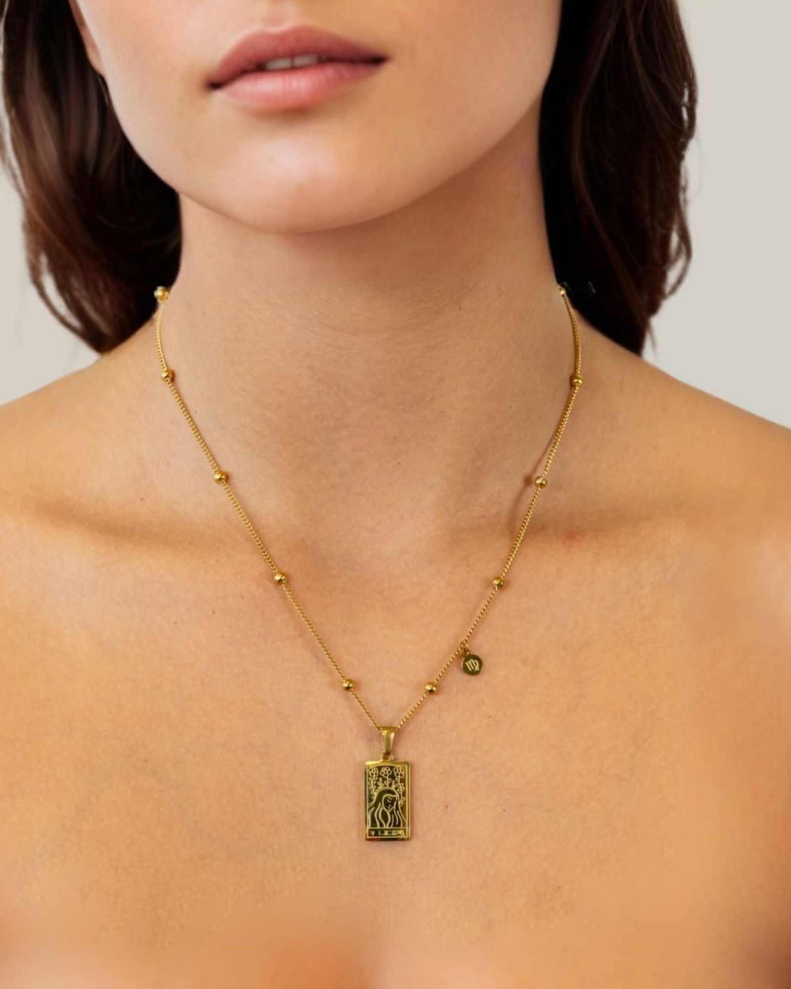 Virgo Gold Zodiac Tag Necklace by Lavana, on model; engraved tag with constellation on beaded chain, front