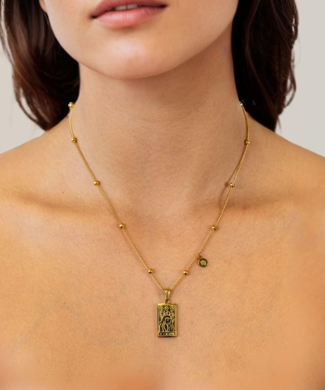 Virgo Gold Zodiac Tag Necklace by Lavana, on model; engraved tag with constellation on beaded chain, front