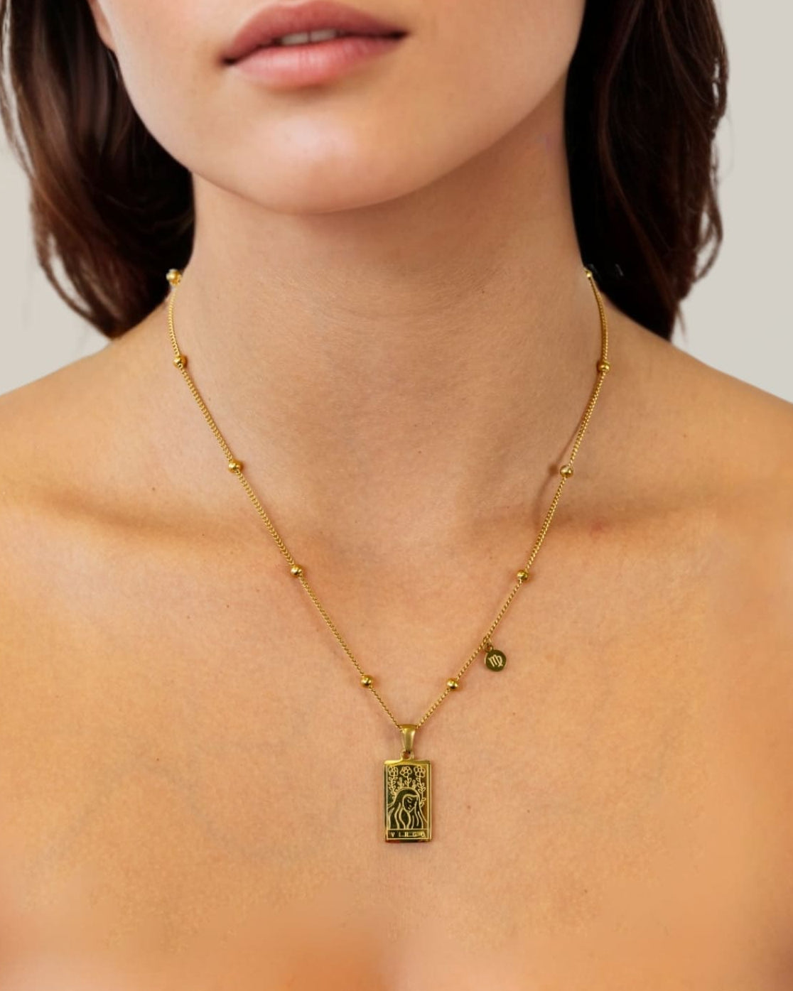 Virgo Gold Zodiac Tag Necklace by Lavana, on model; engraved tag with constellation on beaded chain, front