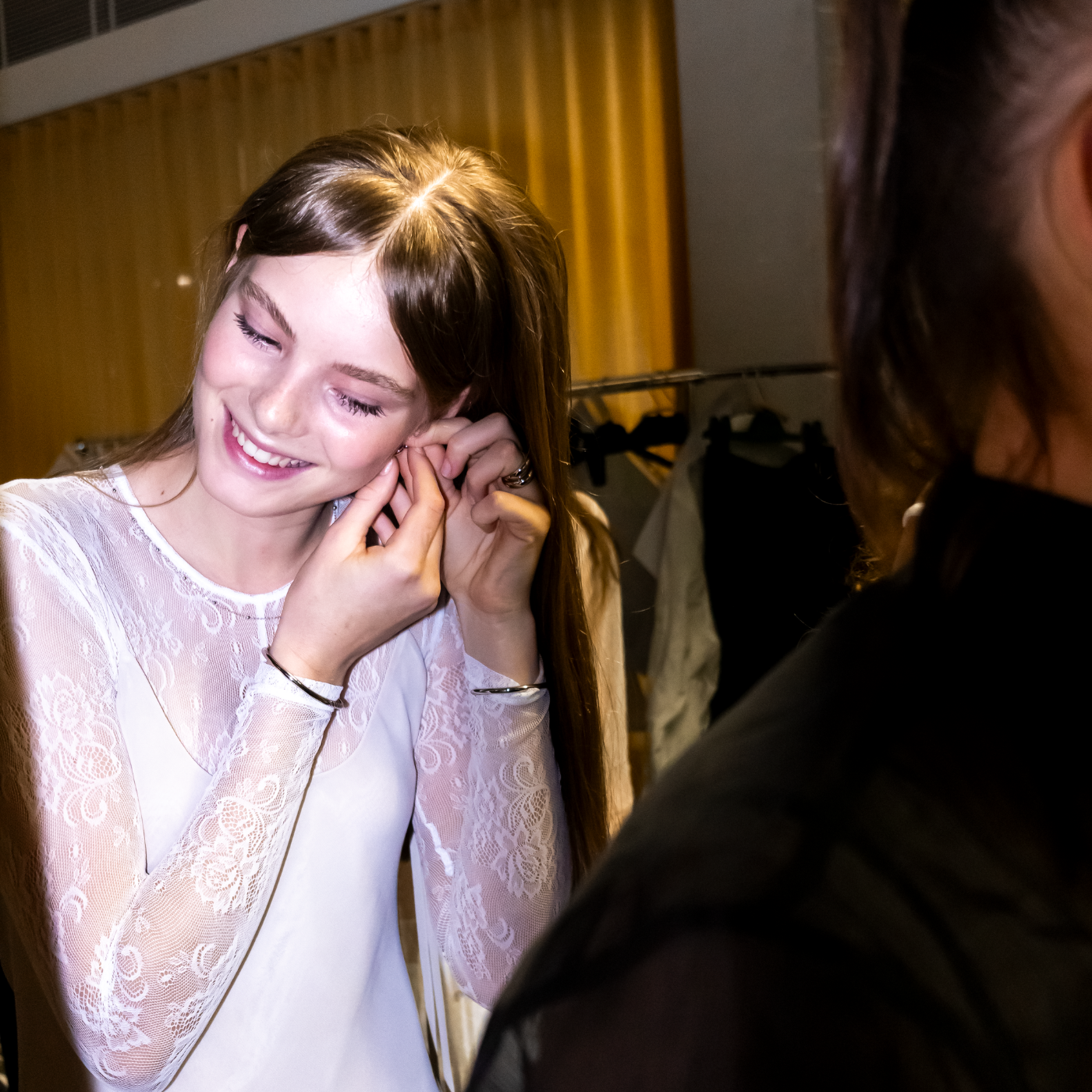 Model adjusting LAVANA earrings with another person partially visible.